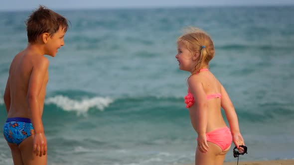 The Little Boy and a Cute Girl are Playing on the Background of the Sea Waves