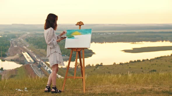 Young Woman Drawing a Painting on Sunset