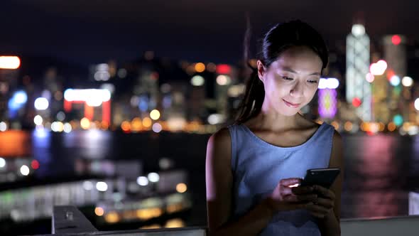 Woman use of mobile phone in Hong Kong city at night 