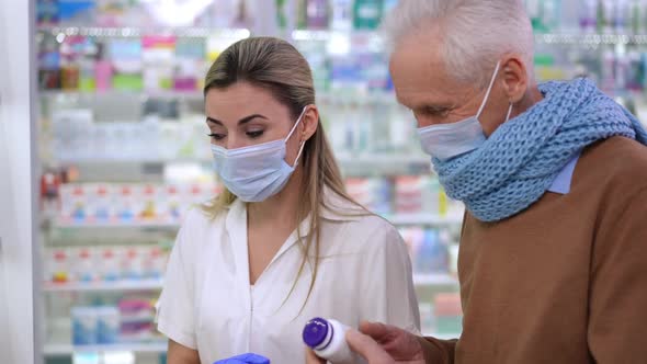 Professional Smart Young Pharmacist Helping Senior Client with Choice of Pills on Coronavirus