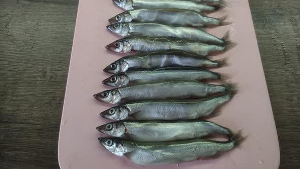 Fresh capelin fish on a cutting kitchen board