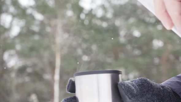 Slow Motion Closeup of a Man Pouring Hot Tea From a Thermos Into a Mug Outdoors in the Cold Weather