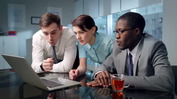 Portrait of Shocked Multiracial Coworkers Looking at Laptop Screen in Modern Boardroom