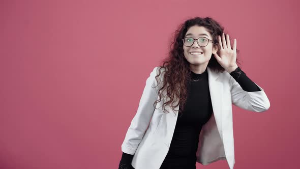 Curious Young Woman with Curly Hair Listens with Her Ear to Her Ear