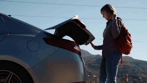 Girl Opens the Trunk of a Car