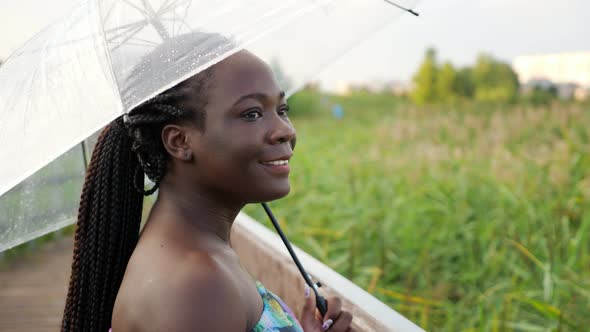 AfricanAmerican Woman with Transparent Umbrella on Bridge