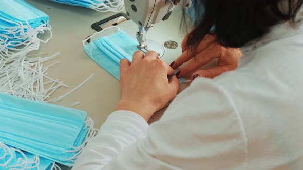 Woman hands using the sewing machine to sew the face medical mask
