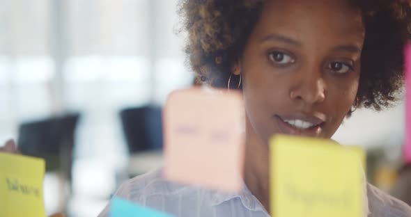 Confident Afroamerican Businesswoman Attaching Stickers To Glass Wall and Brainstorming