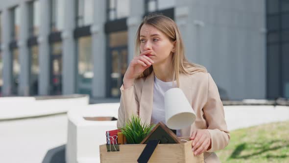 Female Office Worker Sitting Upset with Box of Belongings