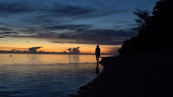 Beautiful sunset on the southern shore og Rarotonga island with a girl barefoot in the lagoon