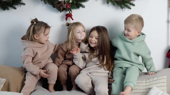 Friendly Children Sit on the Back of the Sofa Near the Christmas and New Year Decorations