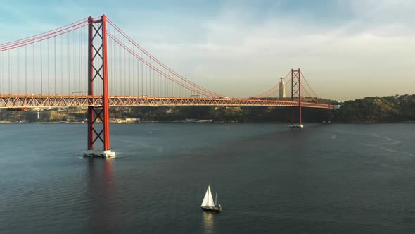 Heavy Traffic Across Car Lanes with a Boat Sailing Under Suspension Bridge