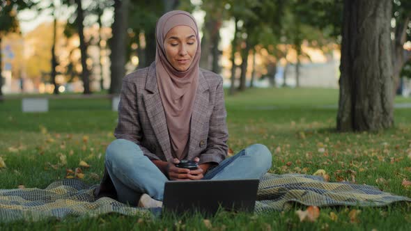 Islamic Muslim Girl Student Online Teacher Business Woman in Hijab Sitting in Park on Green Grass