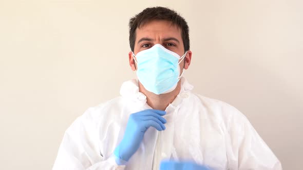 Doctor in PPE suit putting on hood while looking at camera