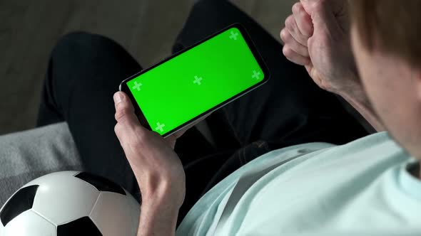 Football Fan Use Smartphone at Home with Green Chroma Key Screen