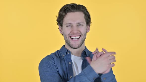 Positive Young Man Clapping and Cheering on Yellow Background