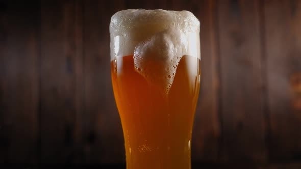 Closeup of a Glass of Light Beer with a Lot of Foam Flowing Down the Glass