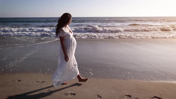 Pregnant Asian woman enjoying walk on the beach