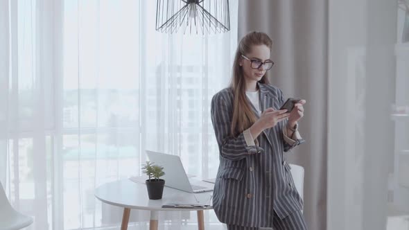 Young Business Woman Looking at Smartphone in the Office