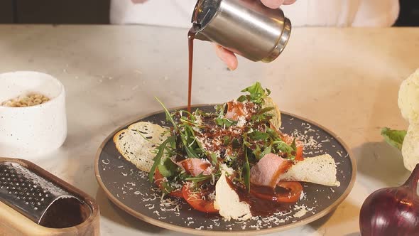 Close Up Hand of Chef Pours Sauce Over a Vegetarian Seafood Salad