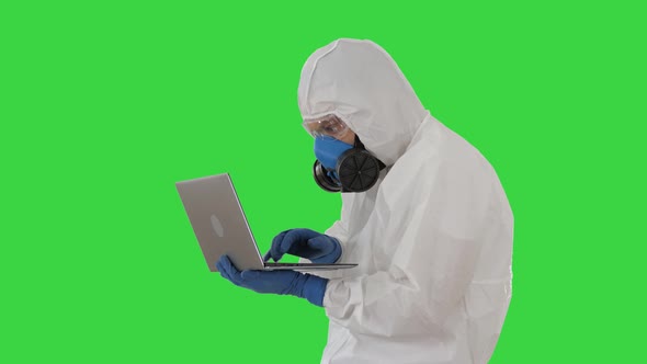 Doctor in Protective Suit Working on Laptop and Having Good Results on a Green Screen, Chroma Key