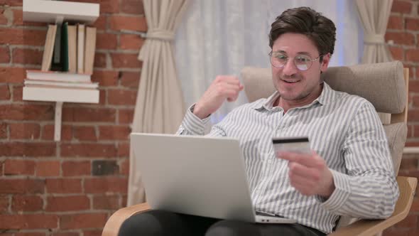 Middle Aged Man making Online Payment on Laptop on Sofa