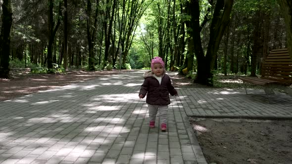 A little girl runs in the park, slow-motion.
