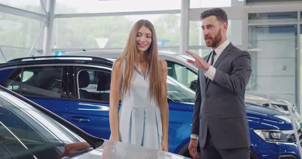 Salesman in Suit Presenting New Car to Female Buyer