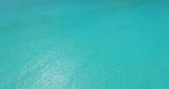 Wide aerial travel shot of a sandy white paradise beach and blue sea background in colourful 4K