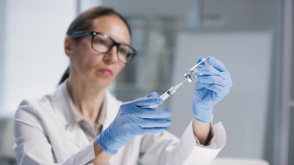 Mature Female Scientist Filling Syringe