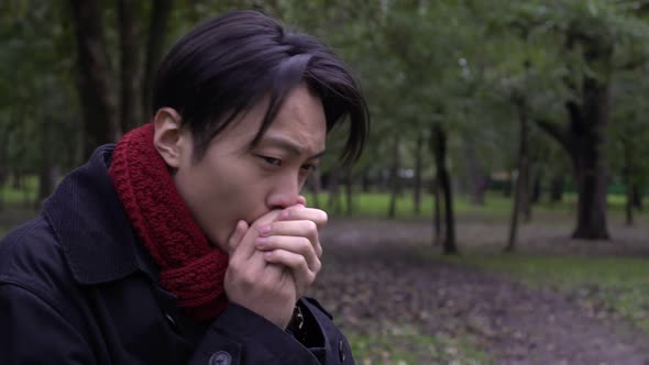 Young Asian Man Freezes in the Park on a Cold Autumn Day