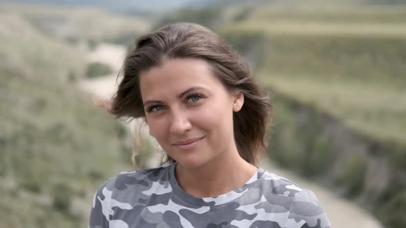 Portrait of an Attractive Girl Tourist in a Gray Suit on a Background of Mountains