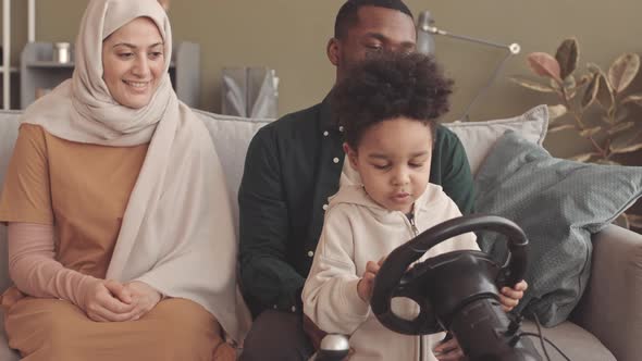 Parents Teaching Little Boy to Play Video Games with Steering Wheel