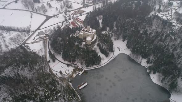 Aerial view of frozen lake and fairy tale castle in the distance at winter