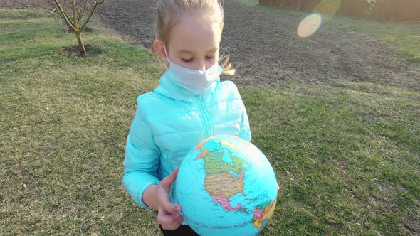 Sad Child Girl in Medical Mask Holding the Globe