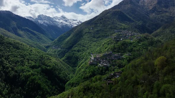Flight above isolated Italian alp village on lush mountain ridge; drone