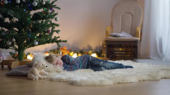Wide Shot Relaxed Carefree Cute Caucasian Boy Lying at Christmas Tree in Living Room Closing Eyes