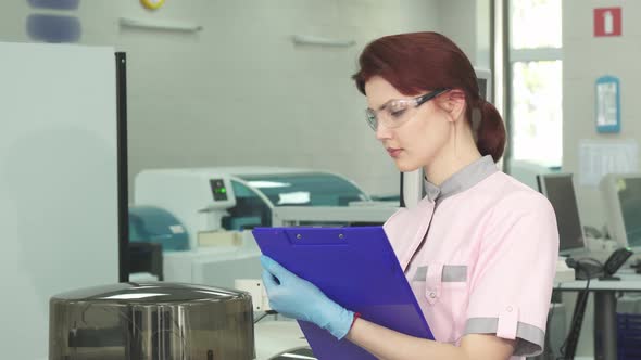 Young Female Scientist Taking Notes at the Modern Lab