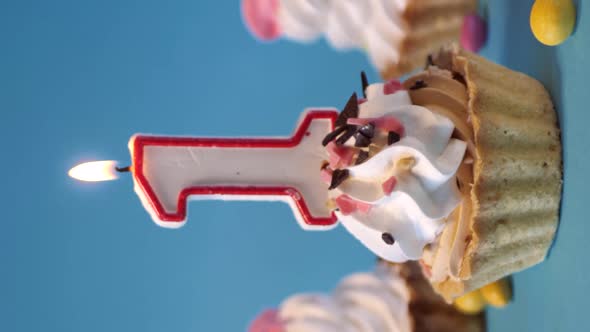 Cake, cupcake for birthday with a burning candle-number one, 1 on a blue background.vertical screen