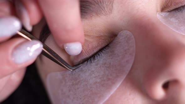 A Young Woman Undergoes an Extension Procedure the Master Removes Old Eyelashes with Tweezers in a