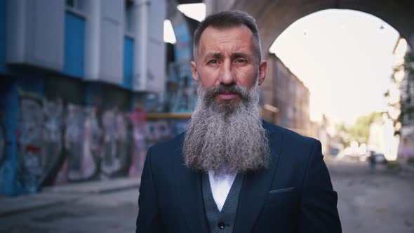 Portrait of Handsome Bearded Mature Man in Suit Lokking in Camera Outdoors in City with Graffiti