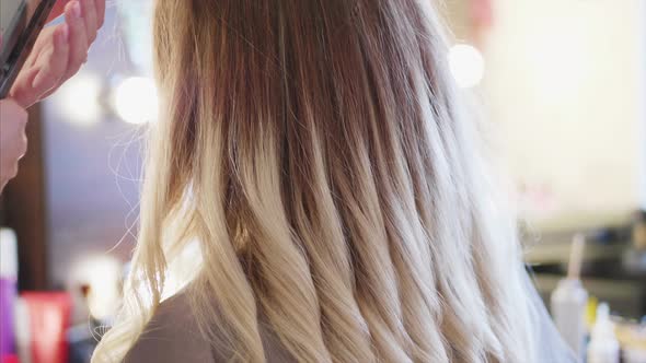 The Hairdresser is Making Curls to Female Client at Beauty Salon