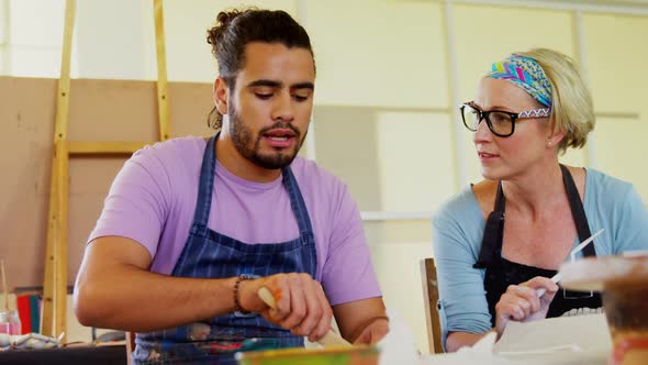 Drawing teacher assisting man in pottery 4k