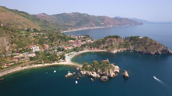 Drone shot of the Isola Bella coastline and the Ionian Sea with boats in the water. Near Taormina, S