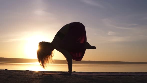 Yoga Bakasana Crane Pose By Woman in Silhouette with Haze Sunset Sky on Background