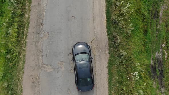 Aerial View of Car Avoiding Potholes On An Old Road