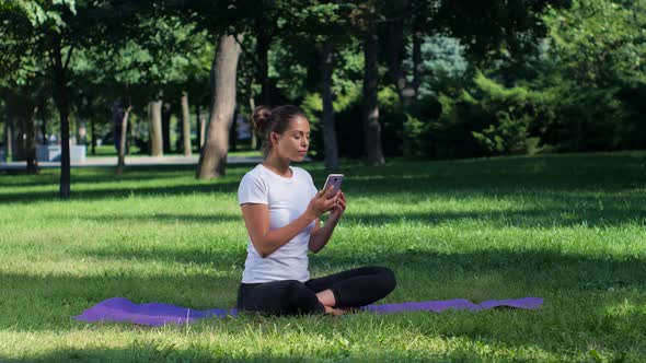Girl Doing Yoga in the Park and Talking on Smartphone