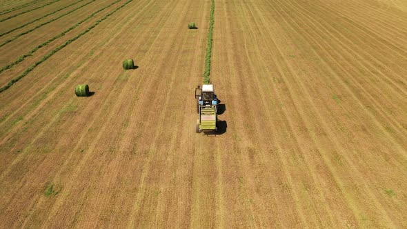 Beautiful view of the field and tractor collecting grass. Agricultural works.