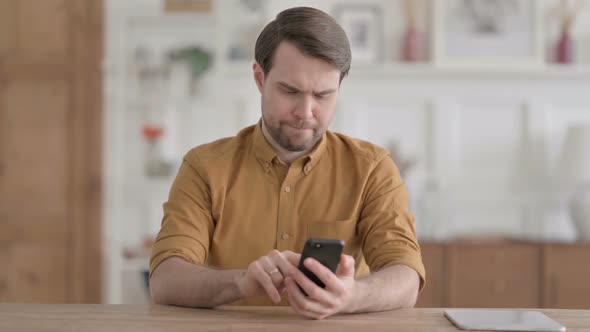 Attractive Young Man using Smartphone in Office