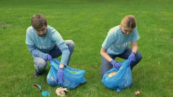 Male and Female Volunteers Picking Up Litter in Park Smiling Each Other, Ecology